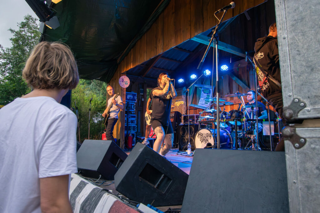 Eine Band performt auf einer Bühne mit einem Mann im Vordergrund.