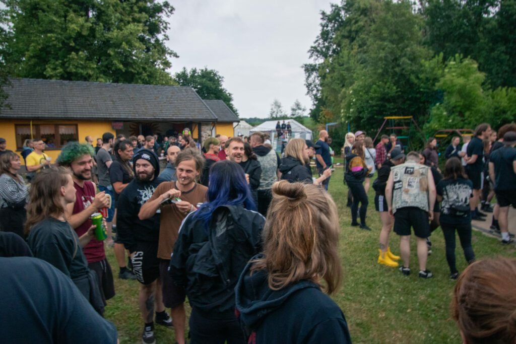 Eine Gruppe Menschen steht auf einer Wiese auf dem Festivalgelände.
