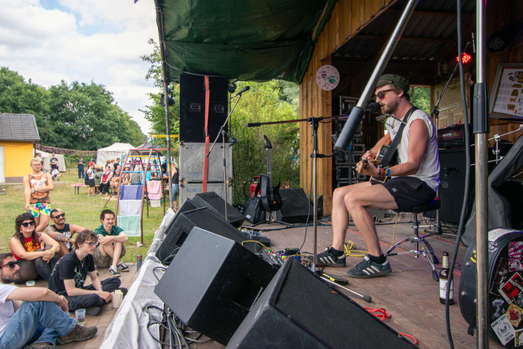 Ein Musiker spielt Gitarre und singt vor einer Gruppe Menschen.