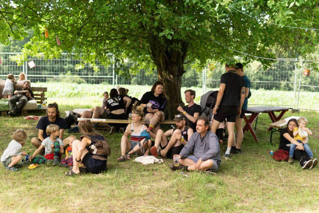 Mehrere Menschen sitzen und unterhalten sich auf dem Festivalgelände
