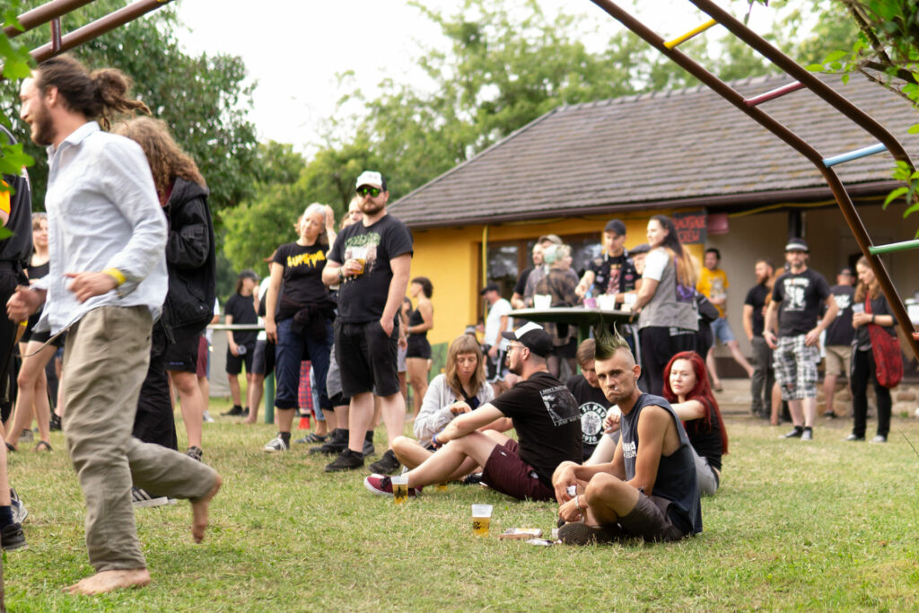 Mehrere Menschen stehen und sitzen auf dem Fesitvalgelände.